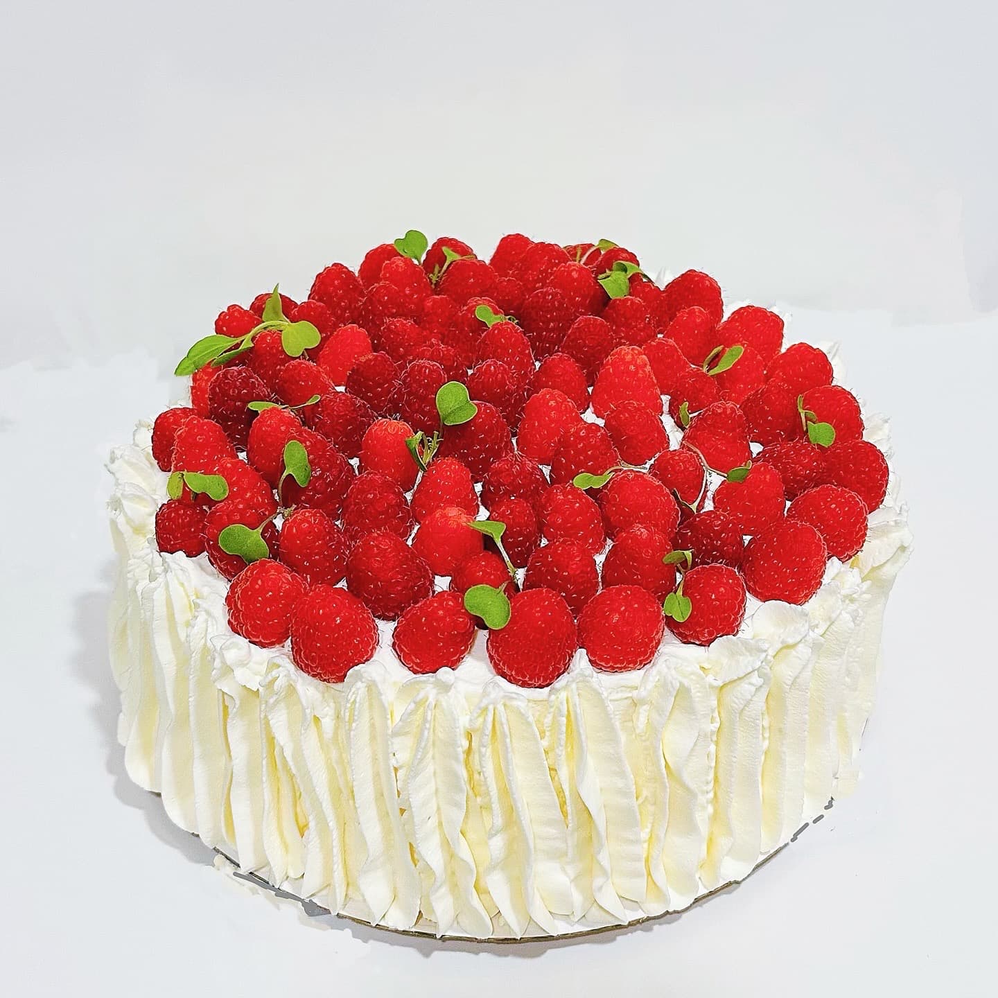 Round raspberry cake with ruffled white frosting