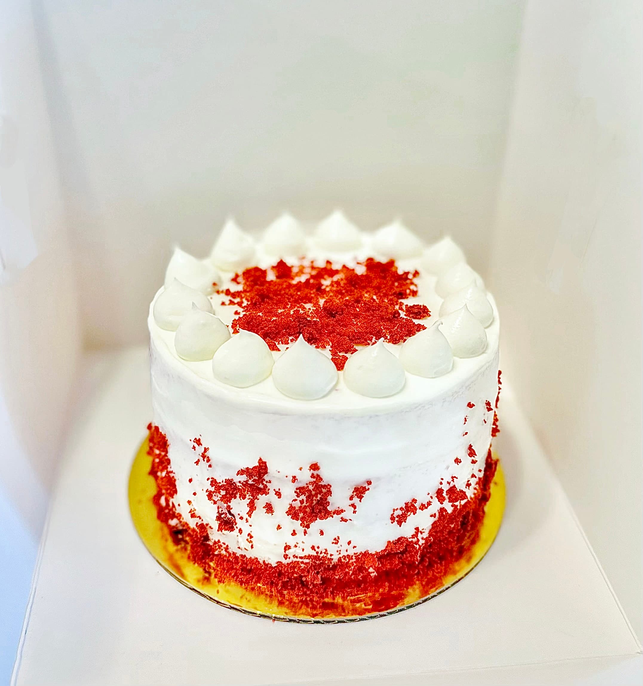 Red velvet cake with white frosting and red crumb topping