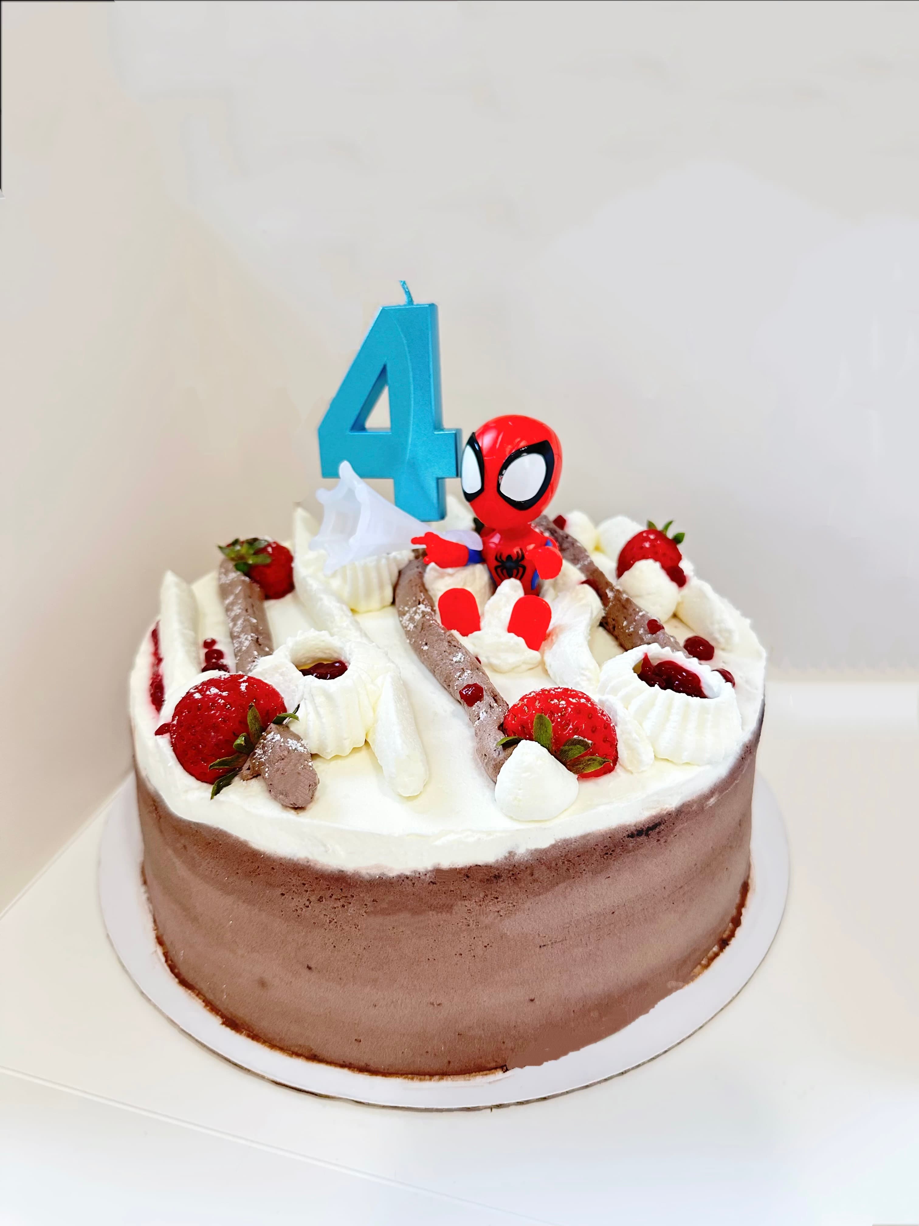 Chocolate cake with white frosting, strawberries, and Spiderman topper