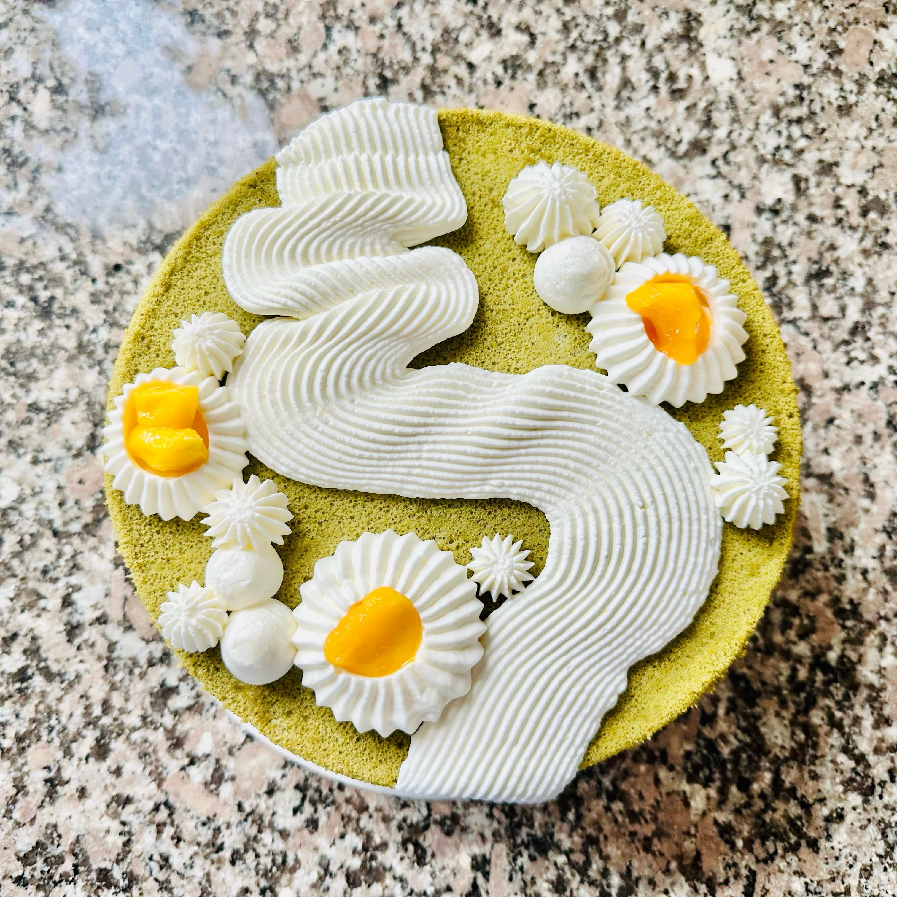 Matcha cake with white cream ribbons and yellow fruit