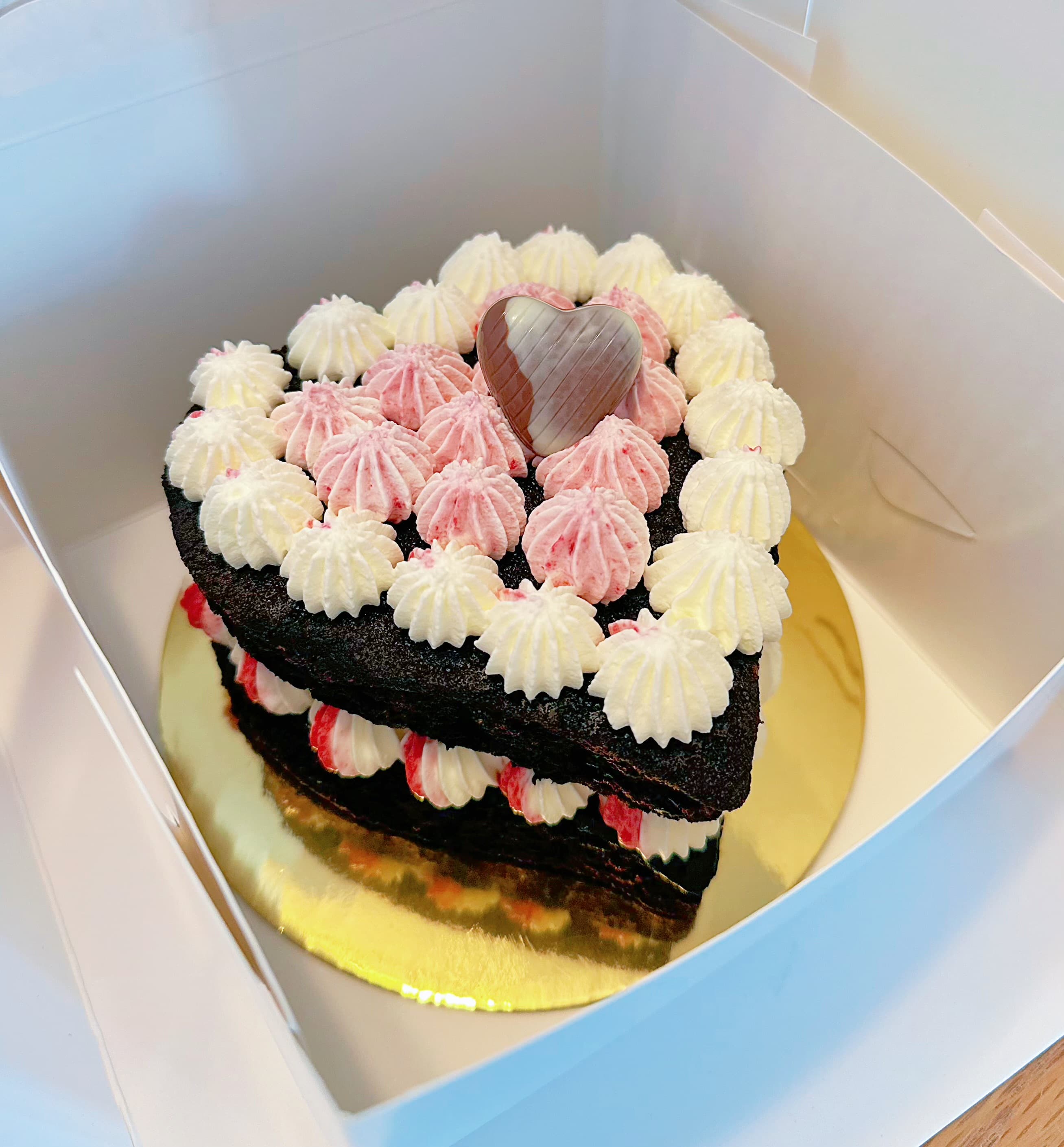 Heart-shaped chocolate cake with white and pink frosting